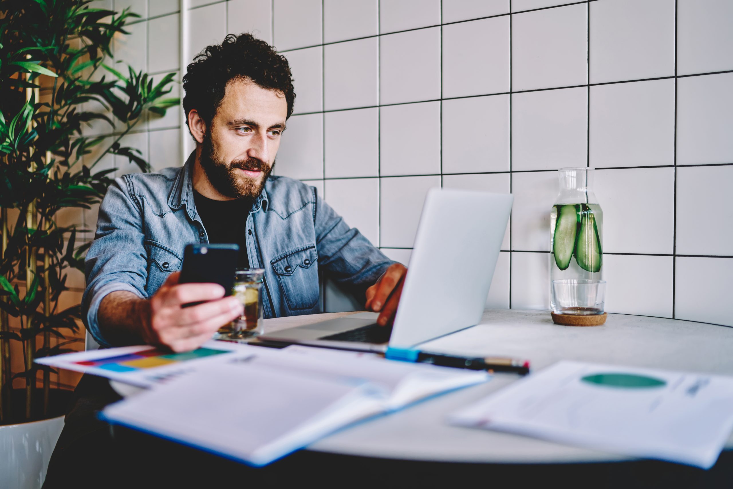 Skilled male freelancer installing app on smartphone for synchro