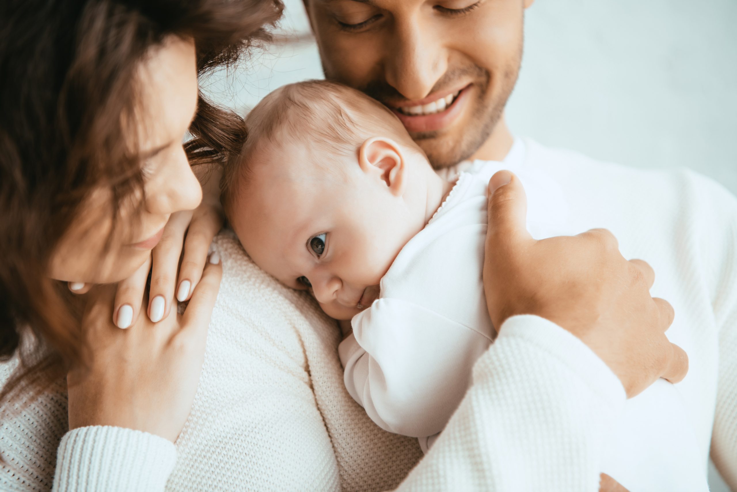 cropped view of happy man holding adorable baby near smiling wif