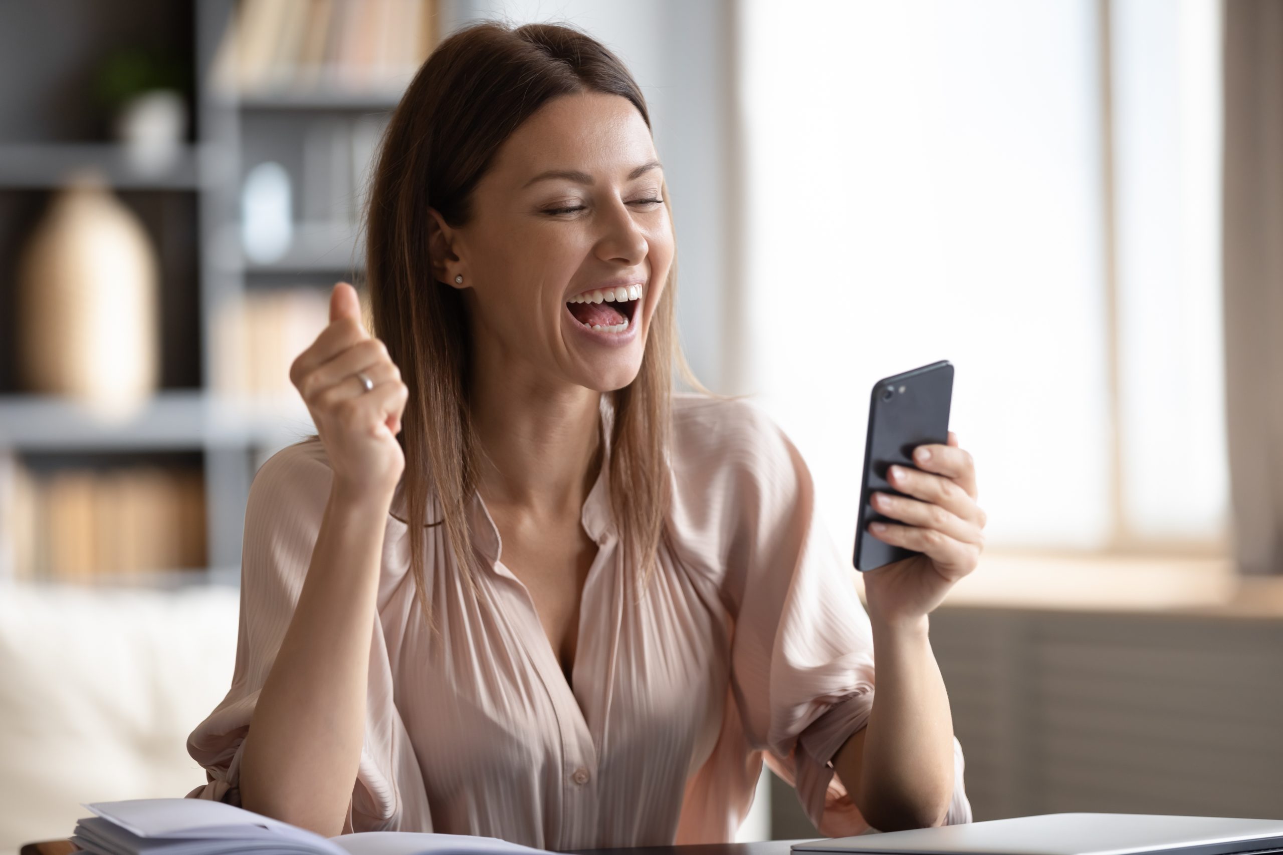 Excited woman looking at phone screen, celebrating online win